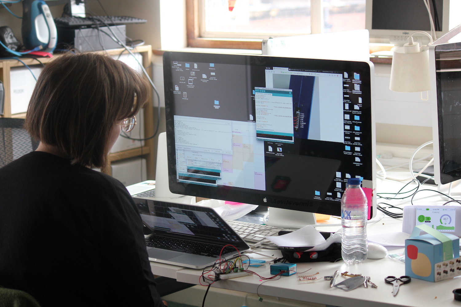 A researcher looks at her screen in an office with lots of electronic equipment around