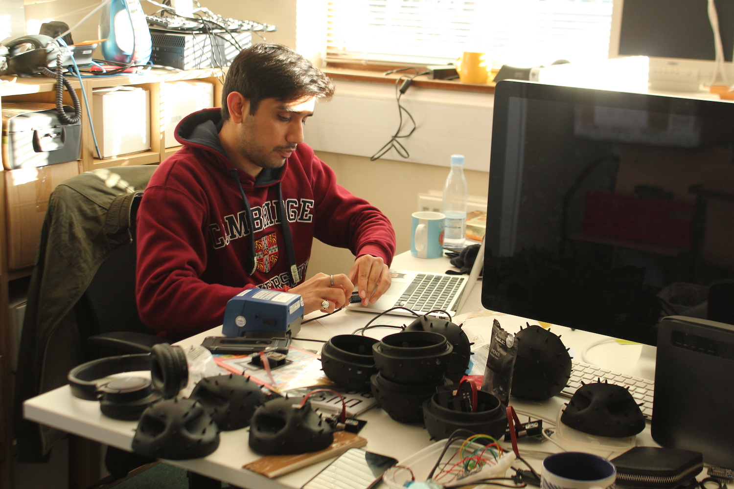 A researchers works at his desk calibrating a sensor. There are Dustbox 2.0 sensors all over the desk